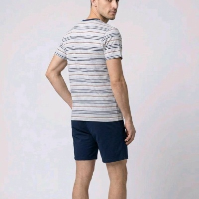 Homem de costas com t-shirt riscada cinza e calções azuis escuros