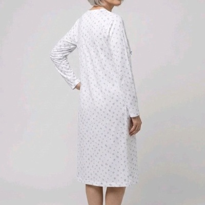 Senhora de costas com vestido comprido branco com padrão de pequenas flores azuis.