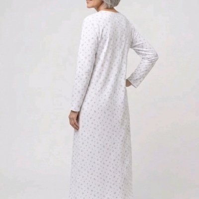 Vestido comprido branco com pequenos padrões florais cinzentos, visto de costas, usado por mulher de cabelo cinza.