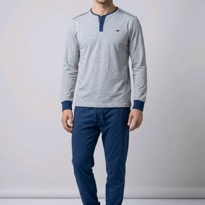 Homem com pijama cinzento e azul, meias cinzentas e chinelos azuis em fundo claro