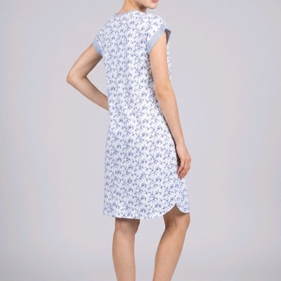 Vestido curto branco com padrão floral azul usado por mulher de costas em estúdio