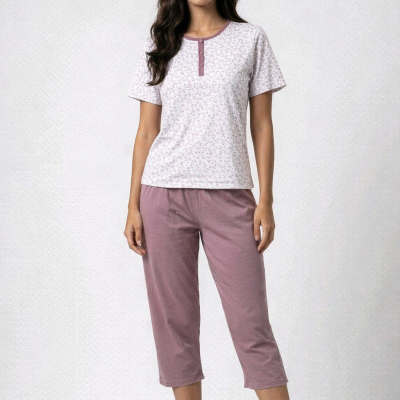 Mulher com conjunto de pijama rosa e branco em fundo neutro