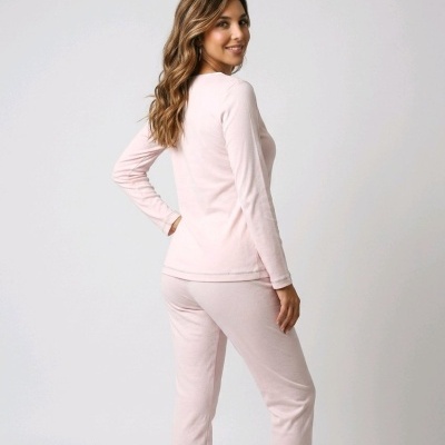Mulher de costas a usar conjunto de pijama rosa claro com camisola de manga comprida e calças.