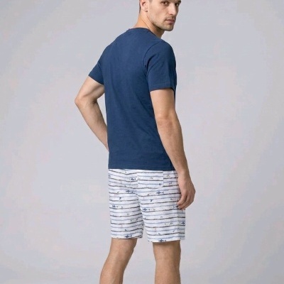 Homem de costas com t-shirt azul e calções brancos listrados com padrão de peixes