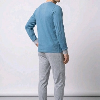 Homem de costas com pijama azul e cinzento e chinelos cinzentos