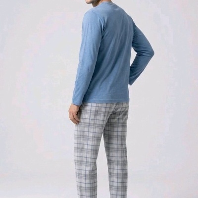 Homem de costas com camiseta azul, calças xadrez cinza e branco e chinelos pretos