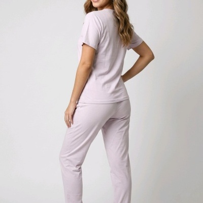 Mulher com conjunto lilás claro de camisola e calças confortáveis e sapatos desportivos brancos num fundo branco