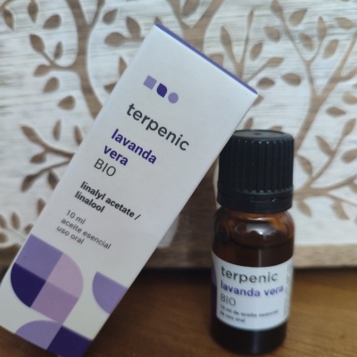 Frasco e caixa de óleo essencial lavanda vera BIO Terpenic sobre mesa de madeira com fundo decorativo