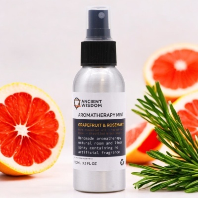 Frasco spray de aromaterapia com toranja e alecrim ao fundo
