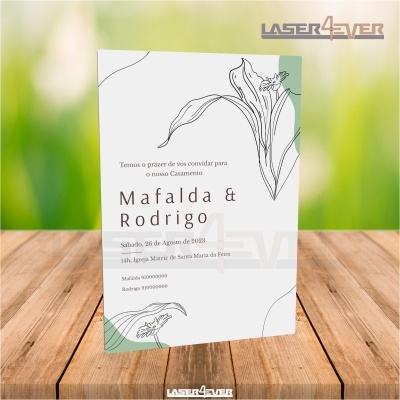 Convite de casamento com design floral em papel branco sobre mesa de madeira