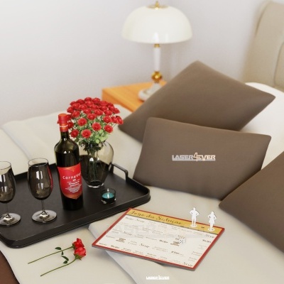 Cama bege com almofadas castanhas, mesa de cabeceira e bandeja com vinho e flores vermelhas