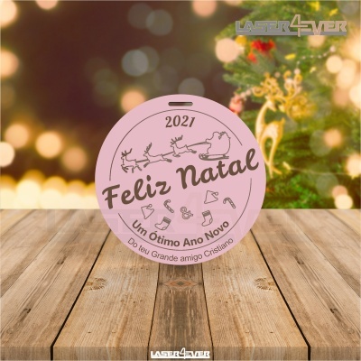 Etiqueta redonda cor-de-rosa com texto e ilustrações de Natal sobre mesa de madeira