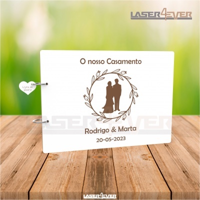 Livro branco decorativo de casamento com nomes e data, em superfície de madeira clara