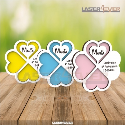 Lembranças de evento em forma de flor com corações amarelo, azul e rosa com texto para aniversário.