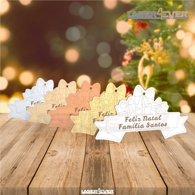 Ornamentos de Natal com texto Feliz Natal em várias cores sobre madeira com árvore de Natal no fundo