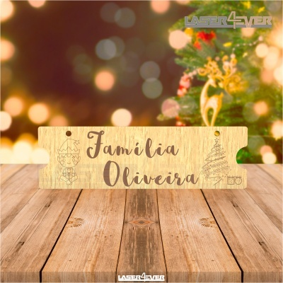 Placa de madeira gravada com texto 'Família Oliveira' em ambiente natalício