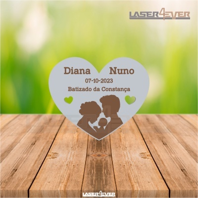 Placa decorativa em forma de coração com texto e silhuetas colocada sobre madeira