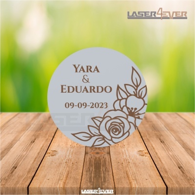 Disco redondo cinzento com texto e padrão floral gravado em castanho sobre madeira clara