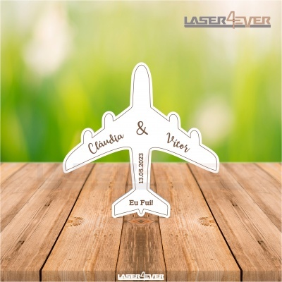 Figura em forma de avião branco com texto em castanho sobre superfície de madeira