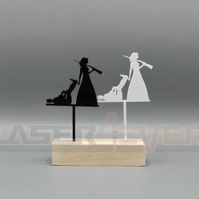 Decoração metálica branca e preta de mulher com espingarda e cão sobre base de madeira clara