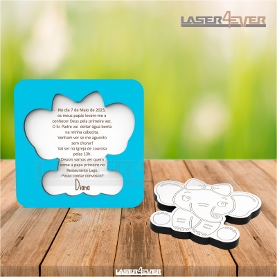 Dois objetos em acrílico em forma de elefante, um com texto e outro com contorno, sobre mesa de madeira e fundo verde desfocado