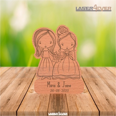 Objeto decorativo em madeira com ilustração de duas figuras femininas e gravação de nomes e data