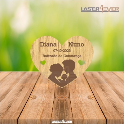 Placa decorativa em forma de coração com texto e silhuetas gravadas a laser, sobre superfície de madeira