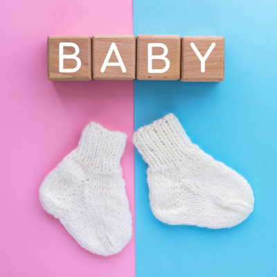 Blocos de madeira com a palavra BABY e meias brancas de bebé sobre fundo rosa e azul