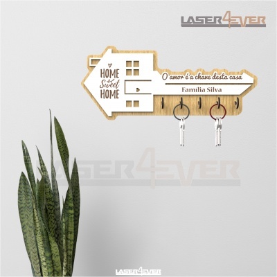 Porta-chaves de parede em forma de casa com texto e três ganchos com chaves, planta ao lado