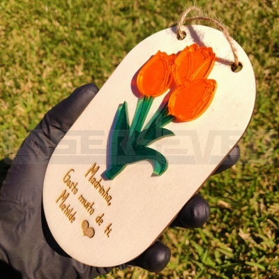 Placa decorativa em madeira com tulipas e texto para madrinha, segurada com mão de luva preta.