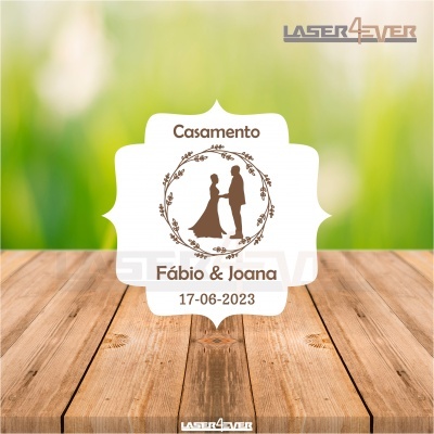 Etiqueta de casamento branca com ilustração castanha de casal e texto com nome e data na madeira.