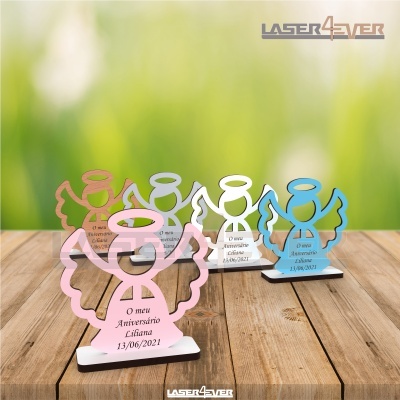 Estatuetas de anjos coloridos em madeira com texto comemorativo em português sobre uma mesa de madeira.