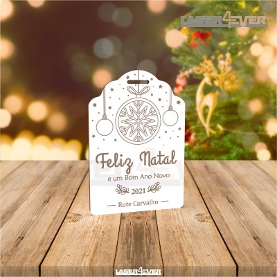 Cartão de Natal branco com texto e desenhos castanhos junto a uma árvore de Natal desfocada