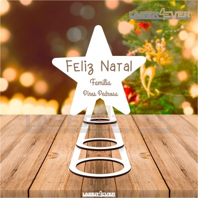 Decoração de Natal em madeira em forma de estrela com texto gravado, sobre superfície de madeira e fundo de luzes natalícias desfocado