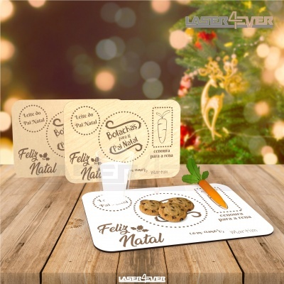 Placas decorativas natalícias com desenhos de cenoura, bolachas e texto Feliz Natal em mesa de madeira