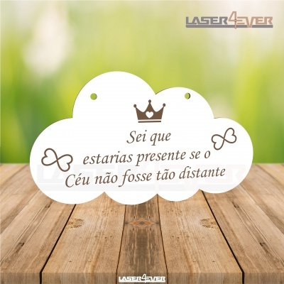 Placa branca em forma de nuvem com texto e desenhos em castanho, sobre madeira, fundo desfocado verde