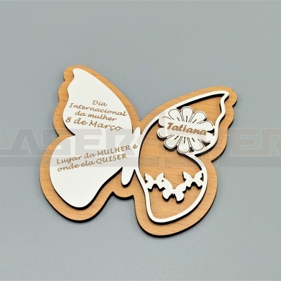 Figura decorativa em forma de borboleta em madeira clara com inscrições em branco