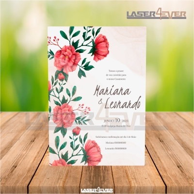 Convite de casamento com flores vermelhas e texto em castanho, sobre superfície de madeira clara