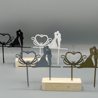 Toppers de bolo decorativos de casais e corações, em metal, com base de madeira clara.