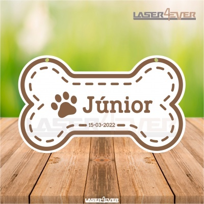 Plaqueta em forma de osso branca com nome Júnior e data numa mesa de madeira