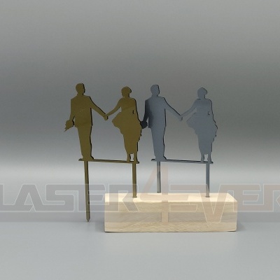 Duas figuras de casal em metal dourado e cinzento em bases de madeira com texto LASER ENGRAVER ao fundo.