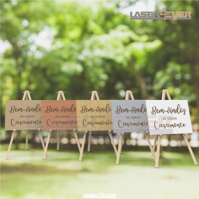 Placas de boas-vindas para casamento em cavaletes de madeira com fundo pastel ao ar livre