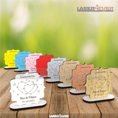 Suportes coloridos para cartões de mesa gravados com 'Casamento', 'Rui & Filipa' e data, dispostos em linha sobre mesa de madeira