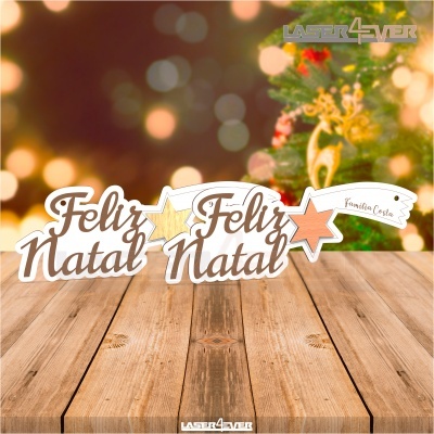 Enfeites de mesa com a mensagem 'Feliz Natal' e estrelas coloridas, fundo com decoração natalícia.