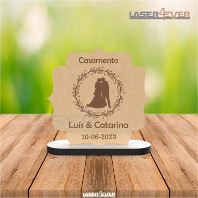 Placa de casamento em madeira com texto Casamento Luís & Catarina na mesa