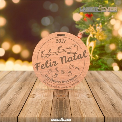 Ornamento de natal redondo em madeira com gravação e decoração natalícia ao fundo