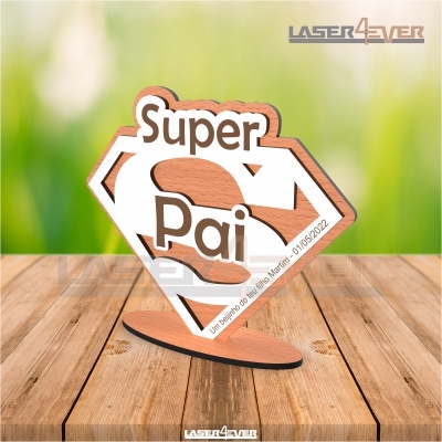 Objeto decorativo em madeira com design do símbolo do Superman e texto 'Super Pai'