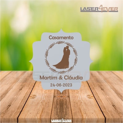 Placa decorativa de casamento cinzenta com texto e silhueta de casal no fundo desfocado verde