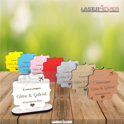 Marcadores de mesa em madeira com texto gravado para casamento, em várias cores e sobre superfície de madeira.