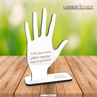 Expositor decorativo de mão branca com texto gravado sobre mesa de madeira